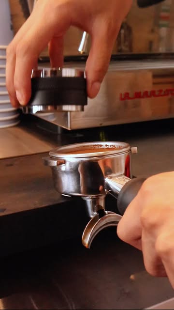 Manos preparando café en un portafiltro de espresso